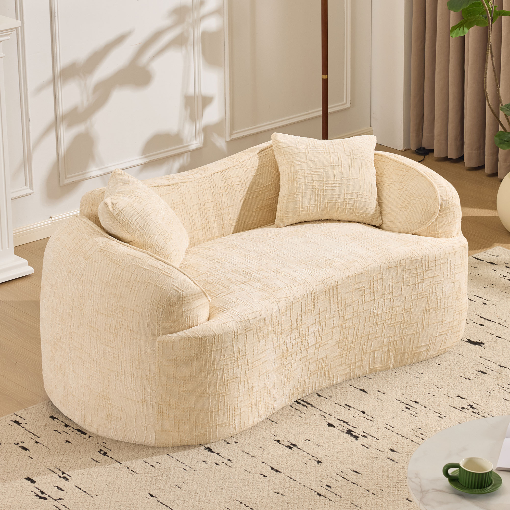Beige curved two - person compress sofa. It has armrests on both sides, comes with two pillows, is suitable for small - sized apartments, and can be placed in the living room or bedroom.